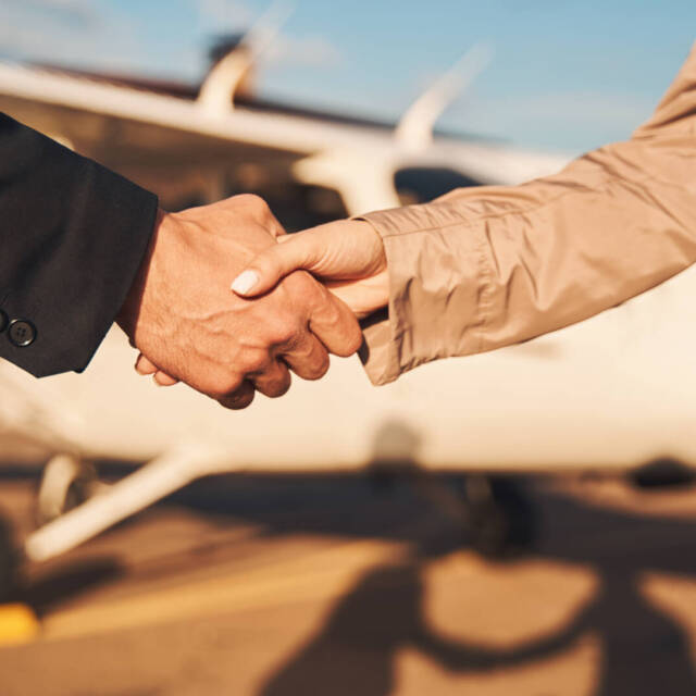 Close up of young man shaking woman hand while making successful deal on sunny day at airfield