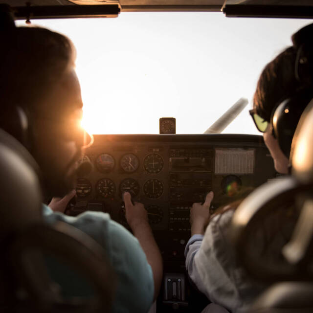 Back view from the inside of the plane, couple in aviation headsets is ready to fly