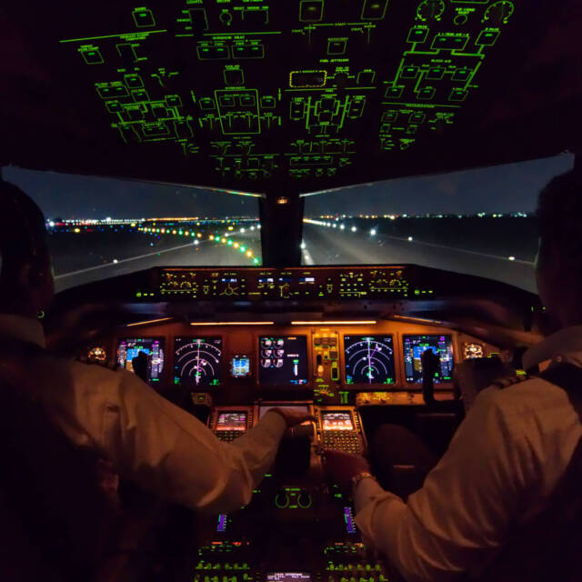 Inside cockpit of commercial airplane after just landed on the runway. Outside window can see beautiful light from airport and inside cockpit can see pilots control airplane. Modern aviation concept.