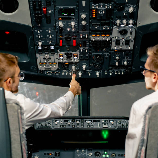 rear view of pilots in the cockpit of an airplane during flight control in turbulence zone flight simulator